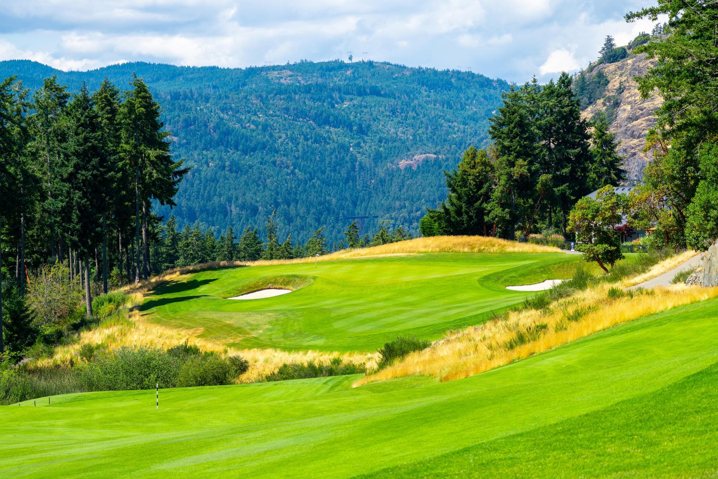 A golf fairway and green below forested hills in Langford