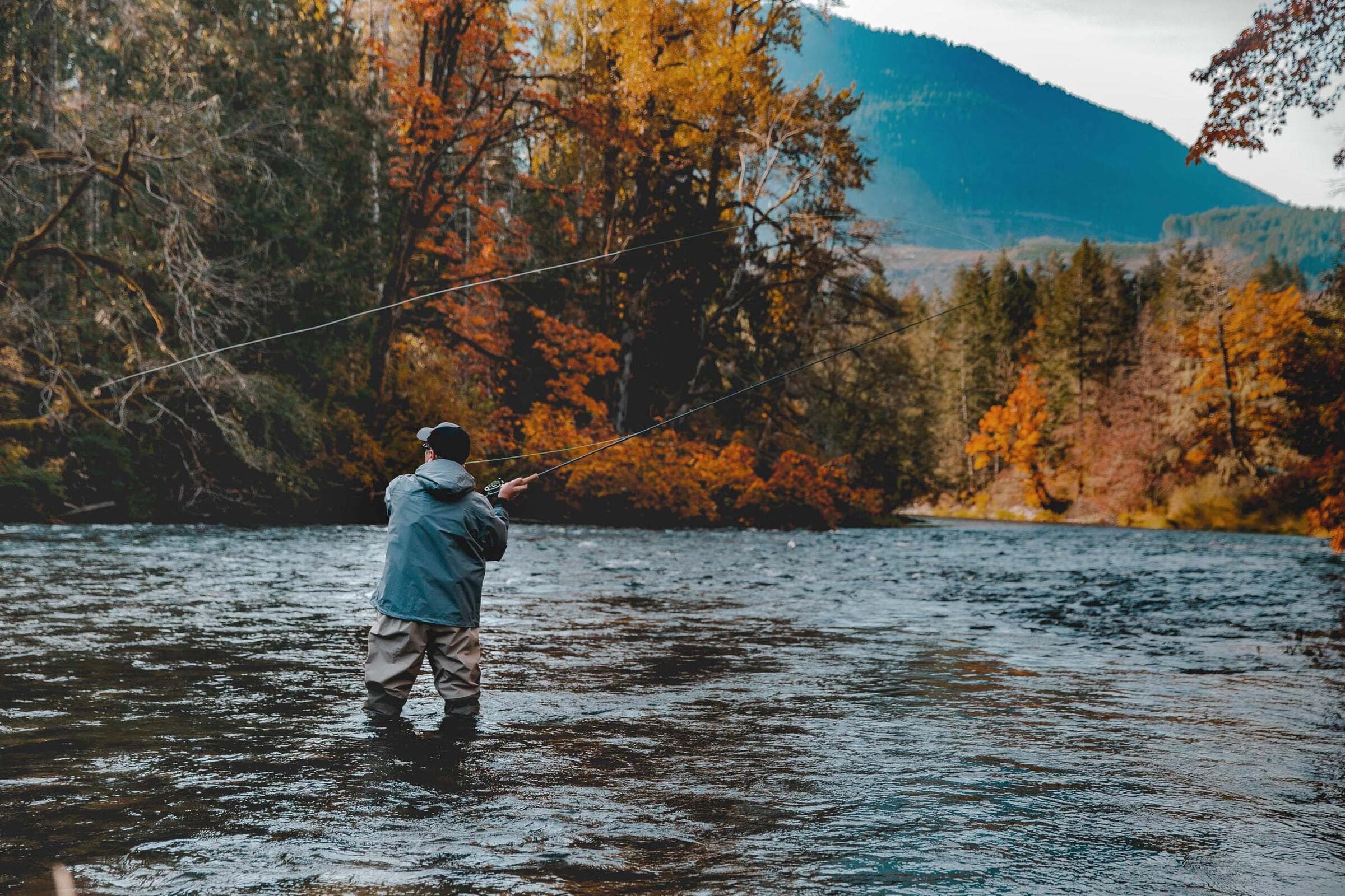 An angler fly fishing the Cowichan River in autumn