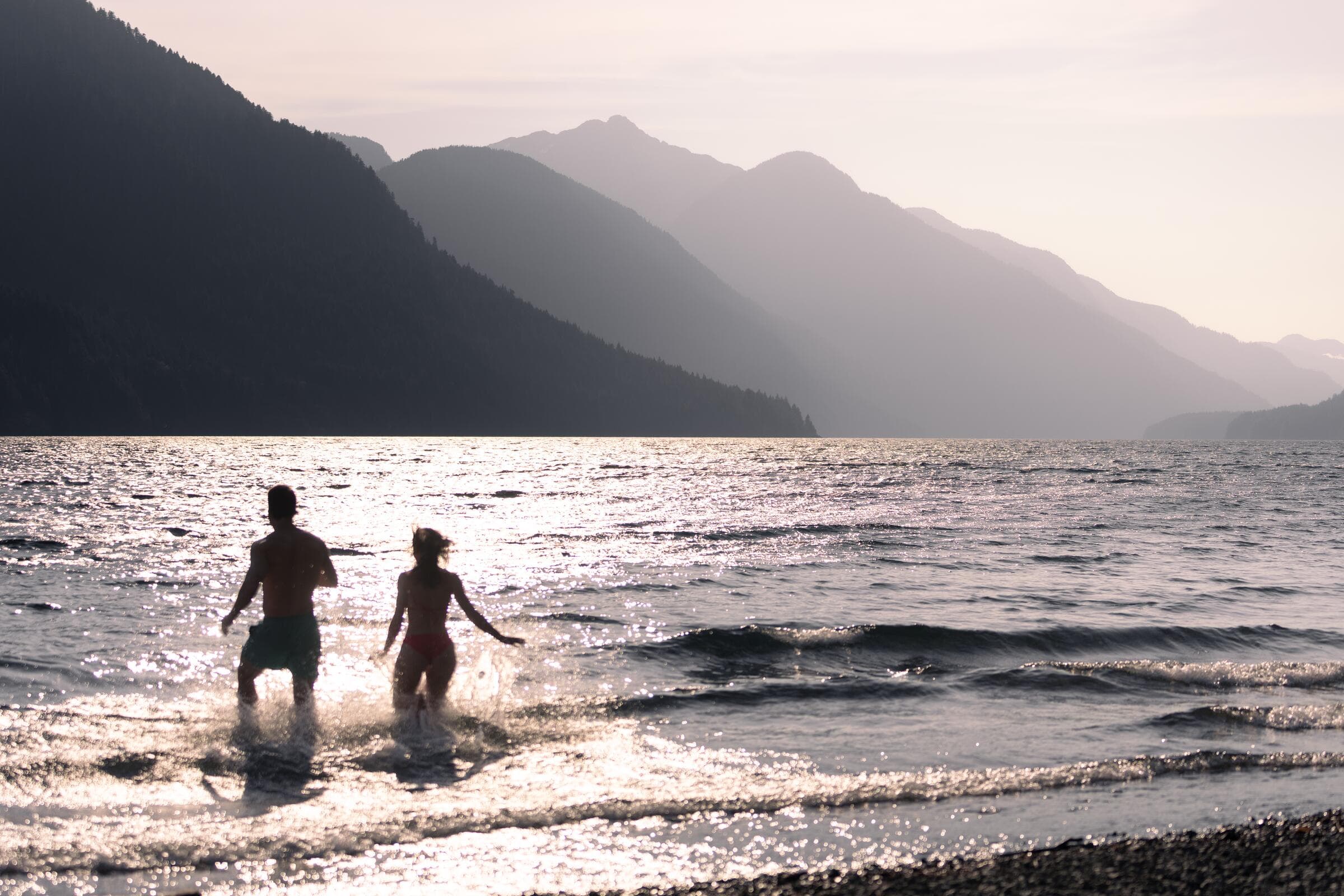 Two swimmers running into Sproat Lake at sunset, Port Alberni