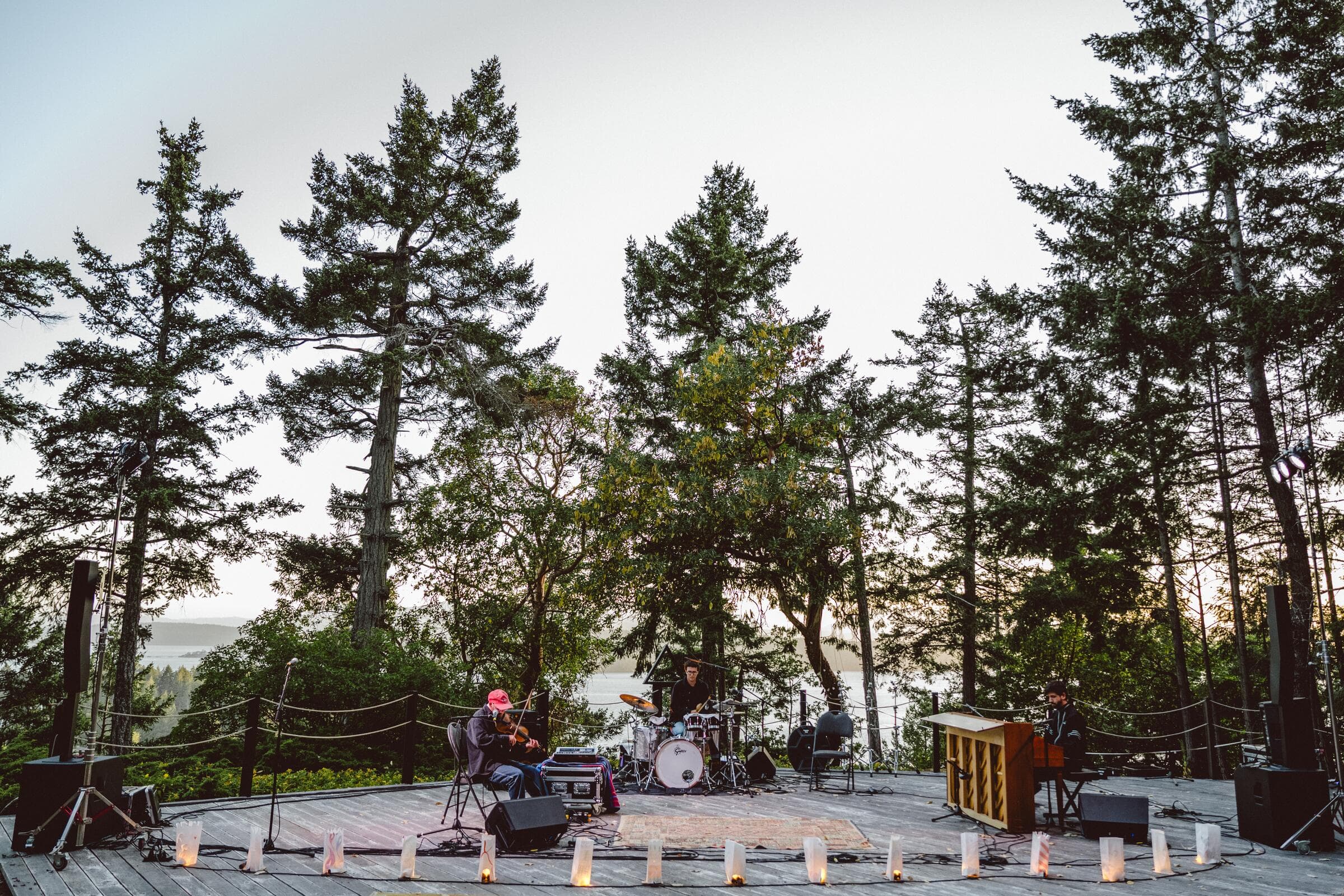 Musicians playing an outdoor concert among tall trees on Mayne Island
