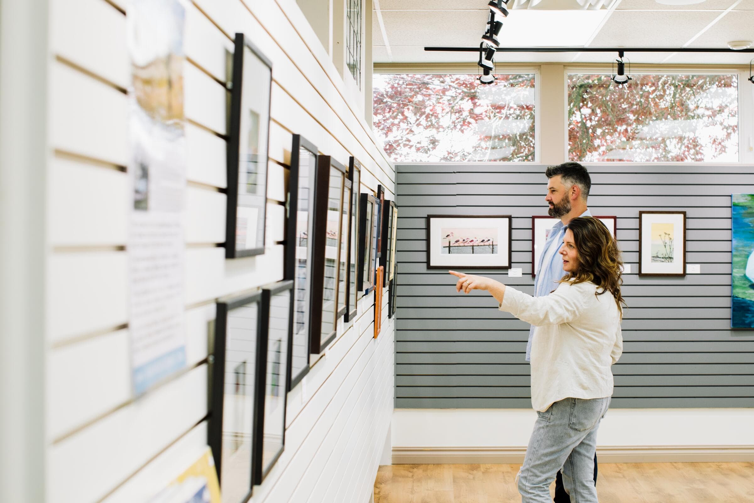 Two visitors looking at paintings in a gallery in Comox
